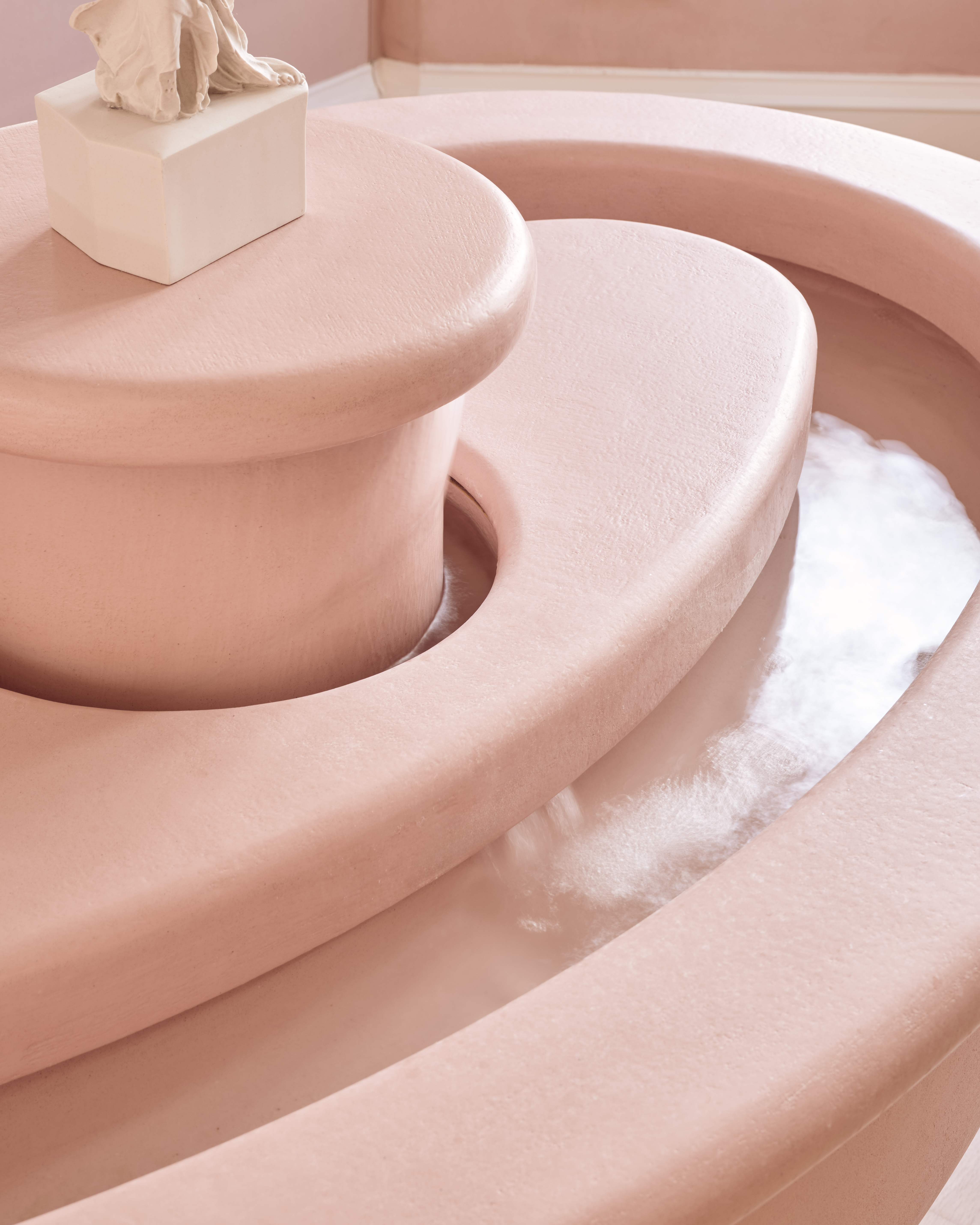 The interior of a beauty clinic with a fountain and a statue.