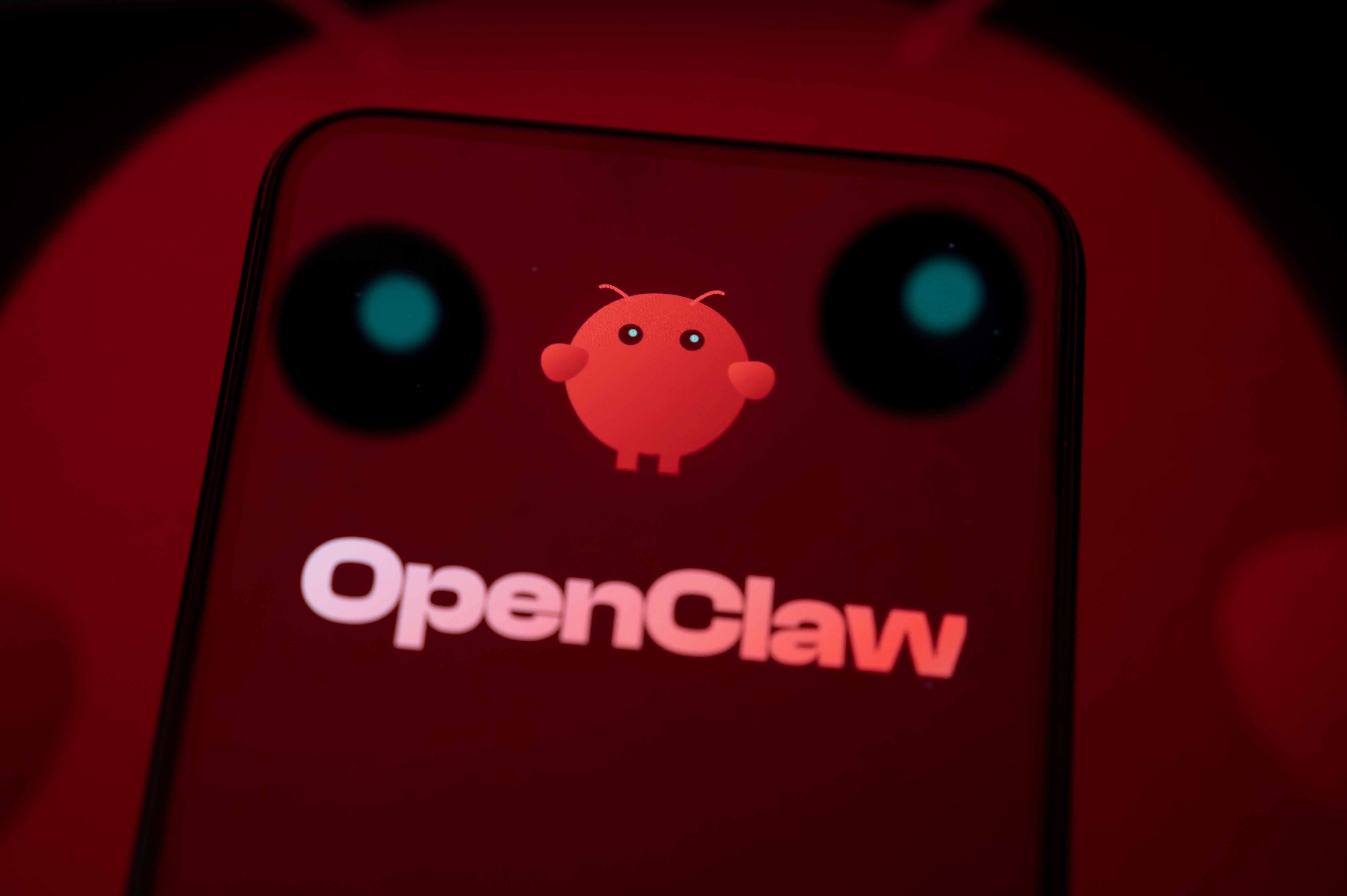 Photo illustration of the OpenClaw AI agent logo and mascot on a smartphone.