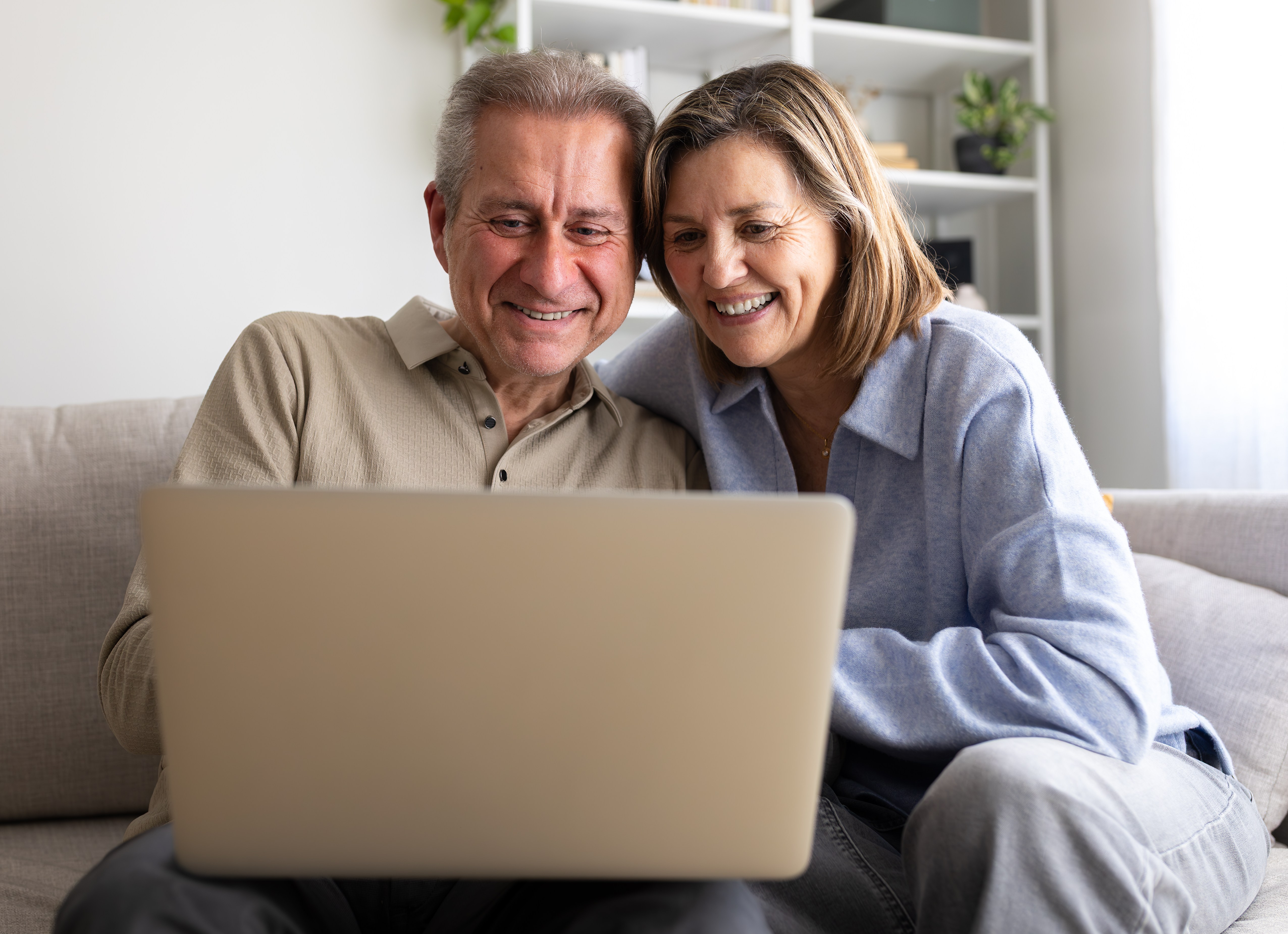 Happy senior couple enjoying using a laptop at home.
