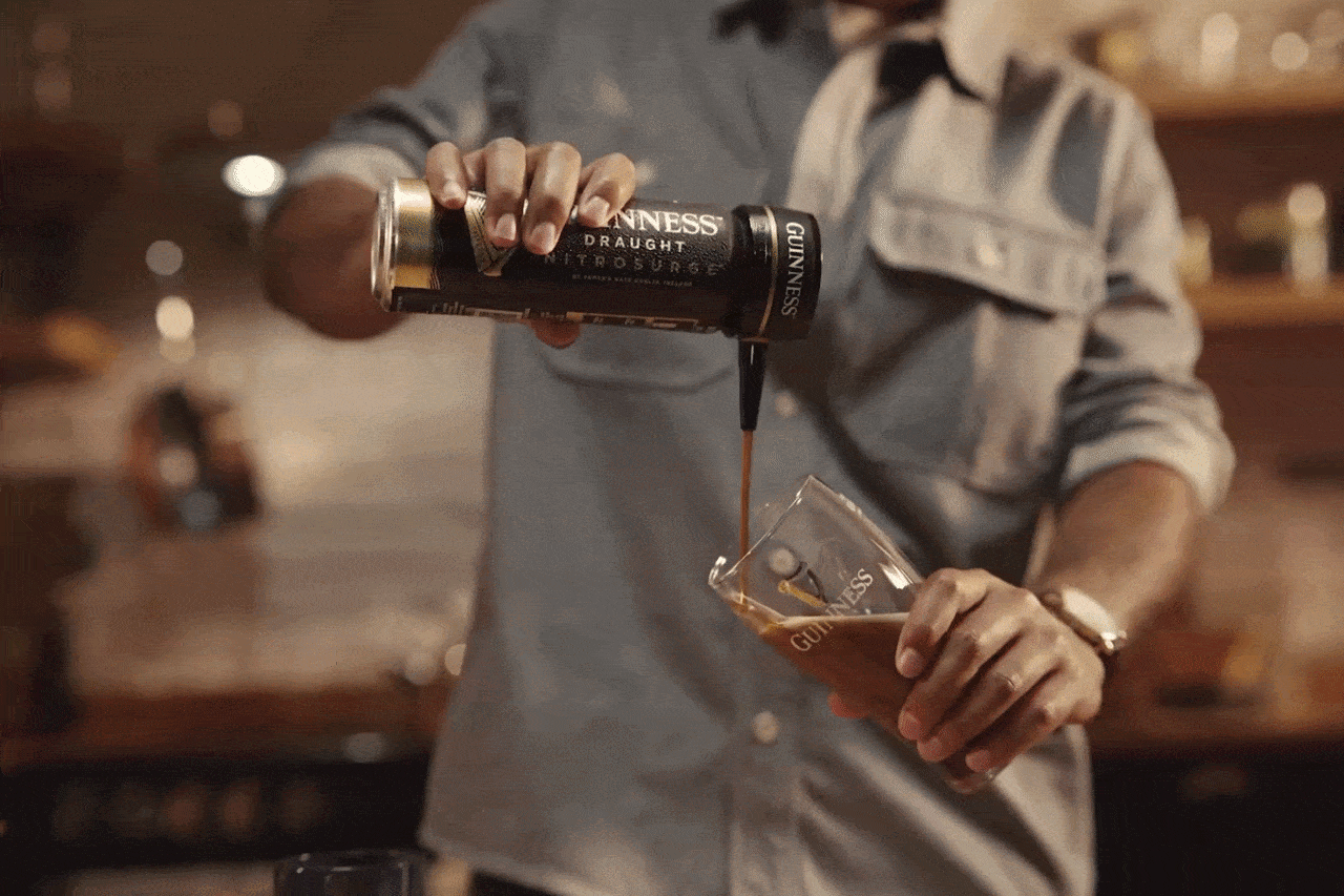 A person pouring Guinness Draught NitroSurge into a Guinness glass.