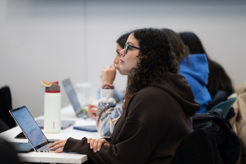 A student with glasses and long hair observing the class.