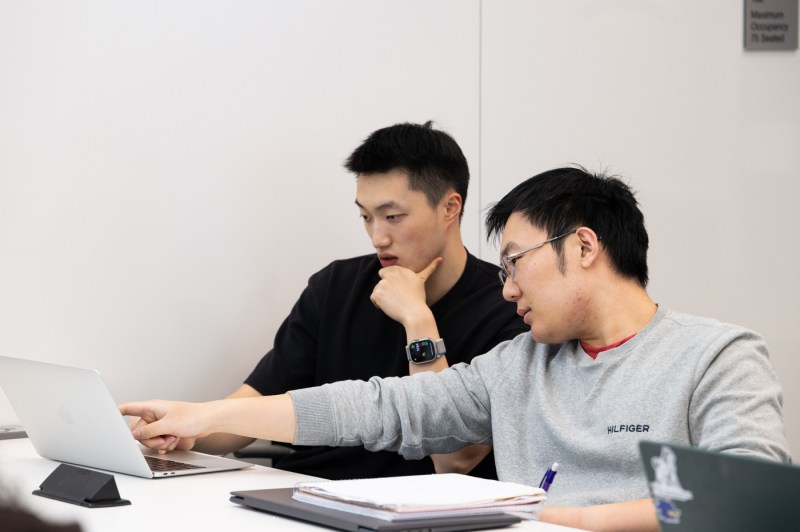 A student points to another student's computer screen.