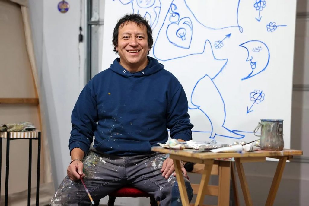 Ernesto "Neto" Atkinson poses in front of a painting he’s working on in his studio. (Photo by Jonathan Aguilar / Milwaukee Neighborhood News Service / CatchLight Local)