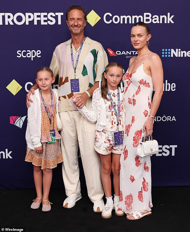 The model stunned in a summery, white slip dress with a red floral print throughout