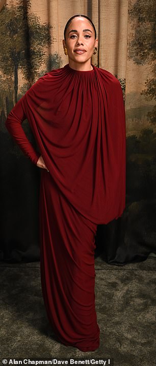 The sports pundit covered up in a ruched red cape-like dress which flowed down tot he floor. Scraping her hair back in a slick bun she accessorised with a pair of gold earrings