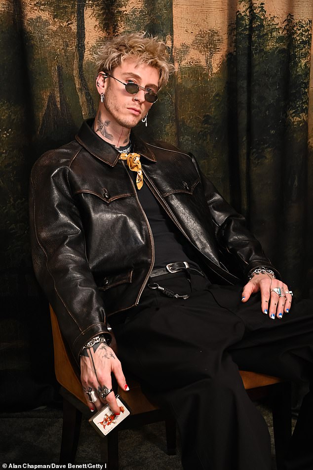 Machine Gun Kelly looked cool in a dark brown leather jacket and yellow necktie