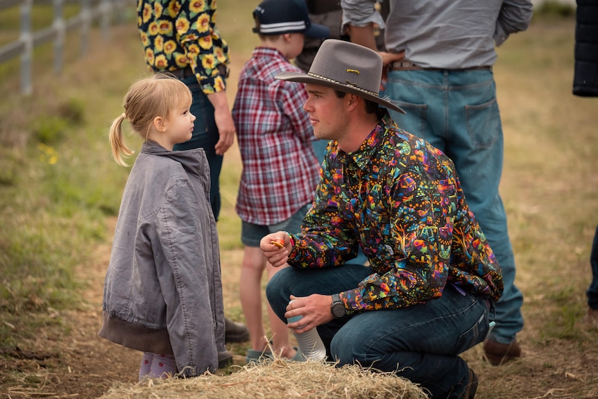 Sam crouches down to talk to his young daughter.