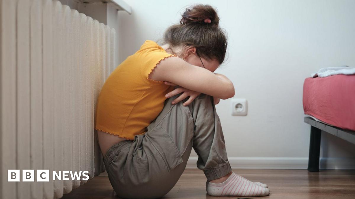 Sad lonely teen sitting on floor near smartphone and crying, feeling depressed.