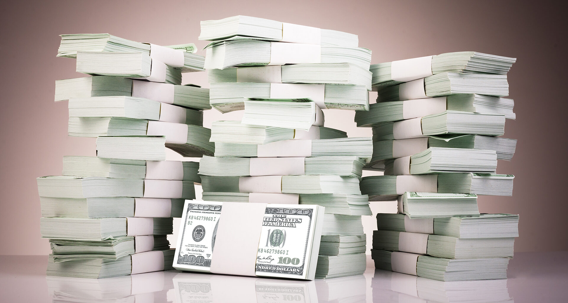 Pile of money stacked on reflective surface.
