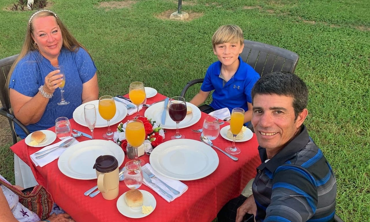 Four people sit at a table outside, smiling