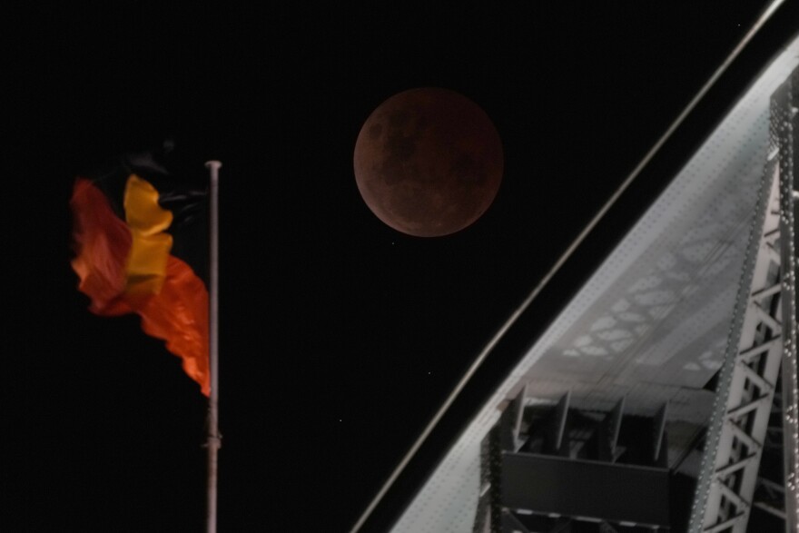 The moon is over the Sydney Harbour Bridge during a lunar eclipse in Sydney, Tuesday, Nov. 8, 2022.