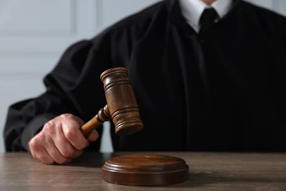 A judge in a black robe holds a gavel, poised to strike, symbolizing authority and justice in a court setting