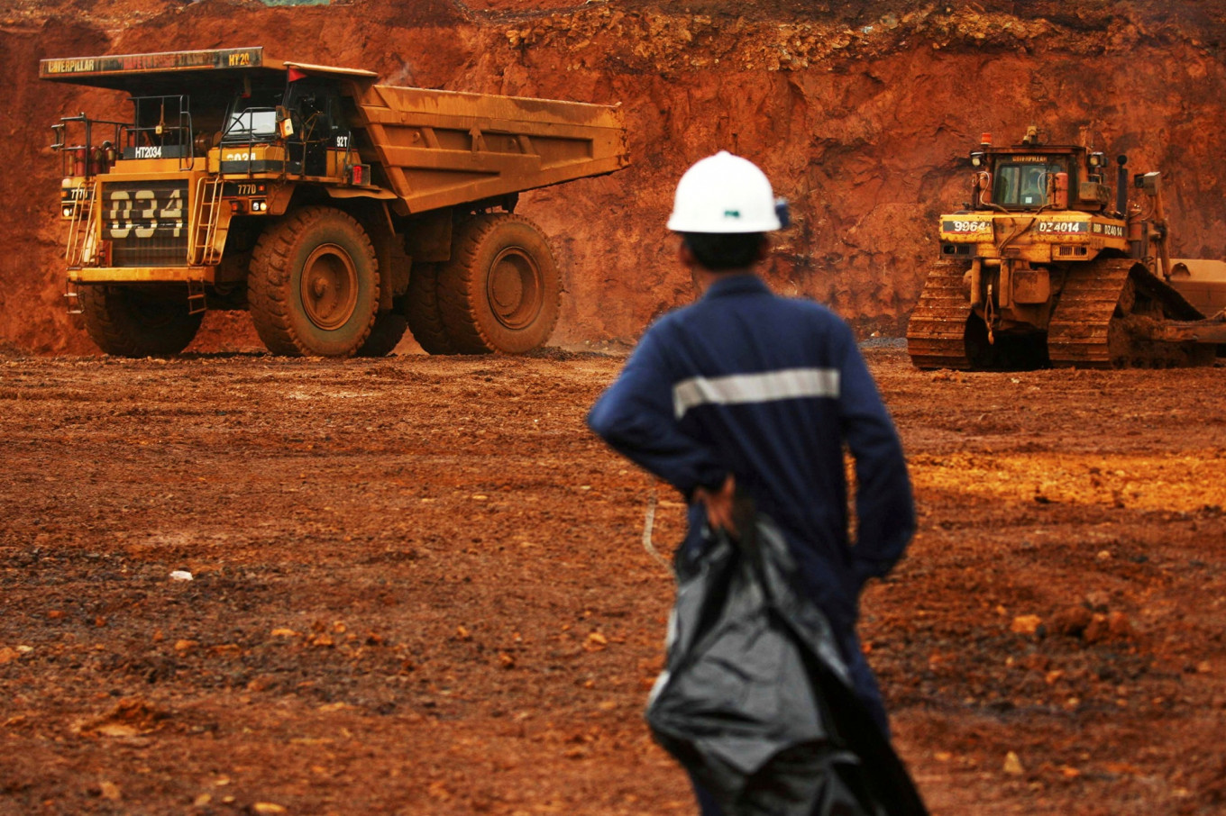 A worker watches as trucks load up raw nickel near Sorowako, South Sulawesi.