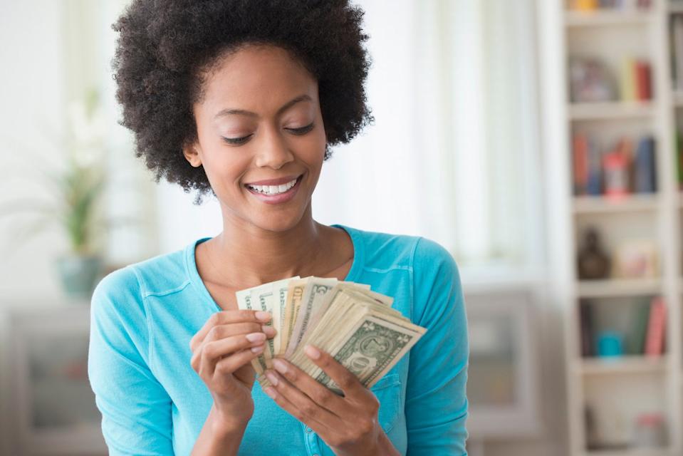 An investor smiles while counting money at home.