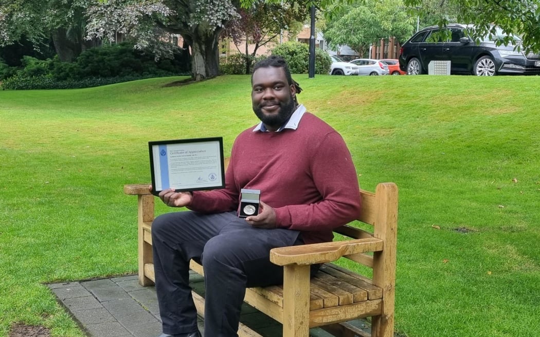 Samson Aruwa on the seat dedicated to Sophia Crestani in Dunedin