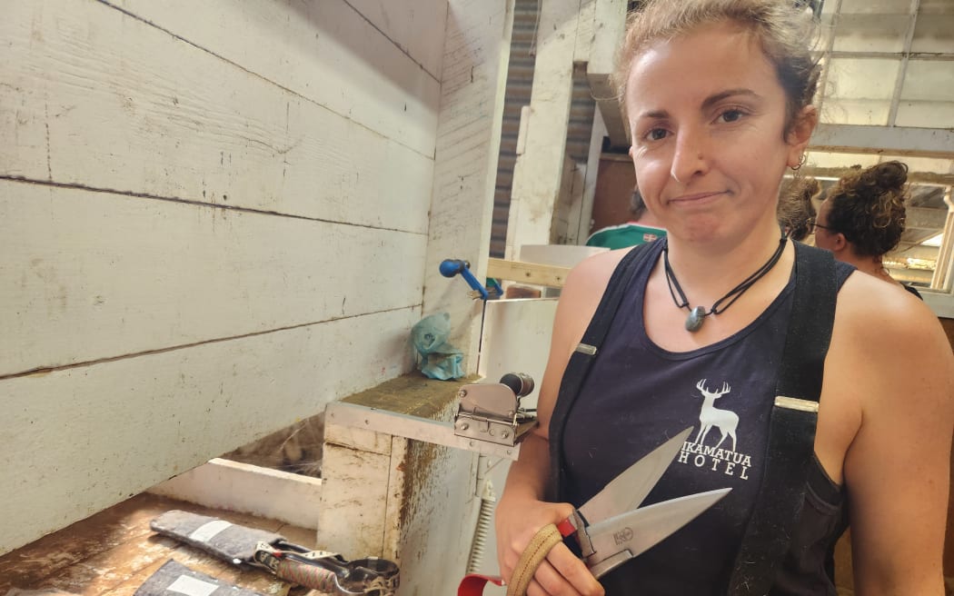 Maureen Cadet in shearer's singlet holding a paiur of blades. She has ten pairs at home in France.