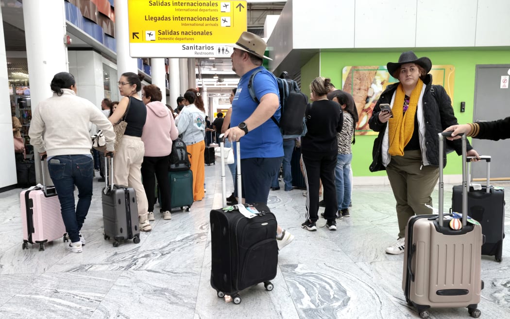 Passengers remain stranded at Guadalajara International Airport following flight suspensions and lack of transport in Tlajomulco, Jalisco State, Mexico, on February 22, 2026. Mexico confirmed on February 22 that soldiers killed a powerful drug cartel leader who was one of the most wanted men here and in the United States. Nemesio Oseguera, the 59-year-old leader of the violent Jalisco New Generation Cartel, was wounded in a clash with soldiers in the town of Tapalpa and died while being flown to Mexico City, the army said in a statement. (Photo by Ulises Ruiz / AFP)