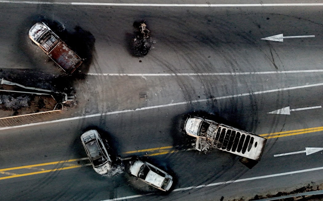 This aerial view shows burned cars and trucks, allegedly set on fire by organised crime groups in response to an operation to arrest a high-priority security target, on a highway near Acatlan de Juarez, Jalisco state, Mexico on February 22, 2026. The Mexican army announced that it had killed powerful drug lord Nemesio 
