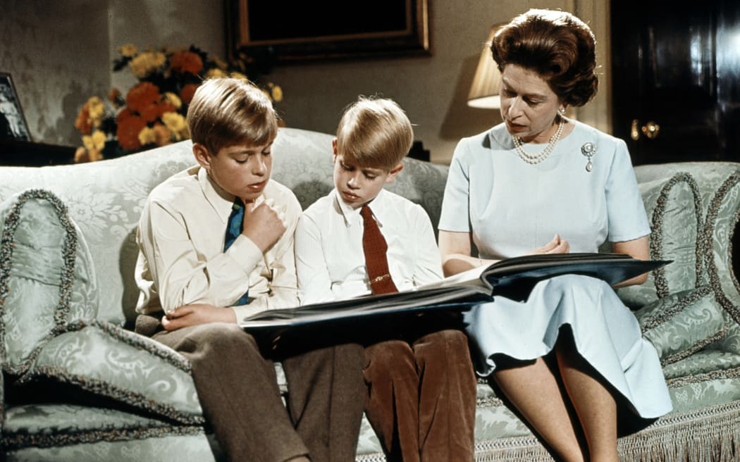 Queen Elizabeth II, with two of her sons Prince Andrew (L) and prince Edward, read a book at Buckingham Palace during the recording of Queen's Christmas message to the Commonwealth which was shown on TV on Christmas day, December 1971. (Photo by CENTRAL PRESS / AFP)