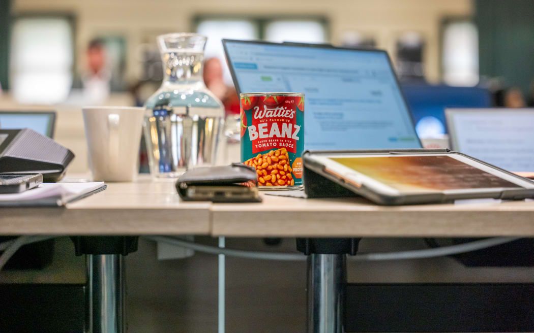 Auckland Mayor Wayne Brown wore a cap with the word 'Rates' on it in a move to mock the governments proposed legislation to cap rates rises. He brought a can of baked beans to the Auckland Council meeting, saying it represents the monthly saving the bill will give to ratepayers.