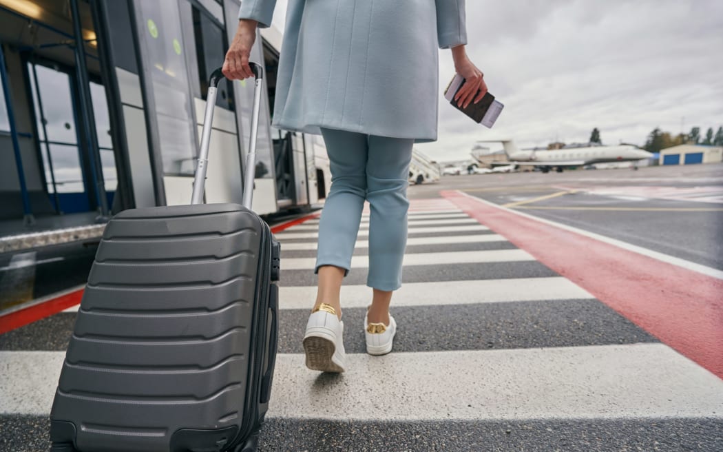 Woman at the airport with her suitcase and passport.
