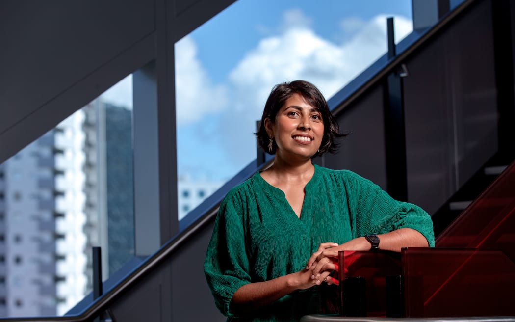 Dr Priyanka Dhopade, research lead of the Sustainable Space Initiative, University of Auckland, standing in front of a window with the Auckland skyline in the background