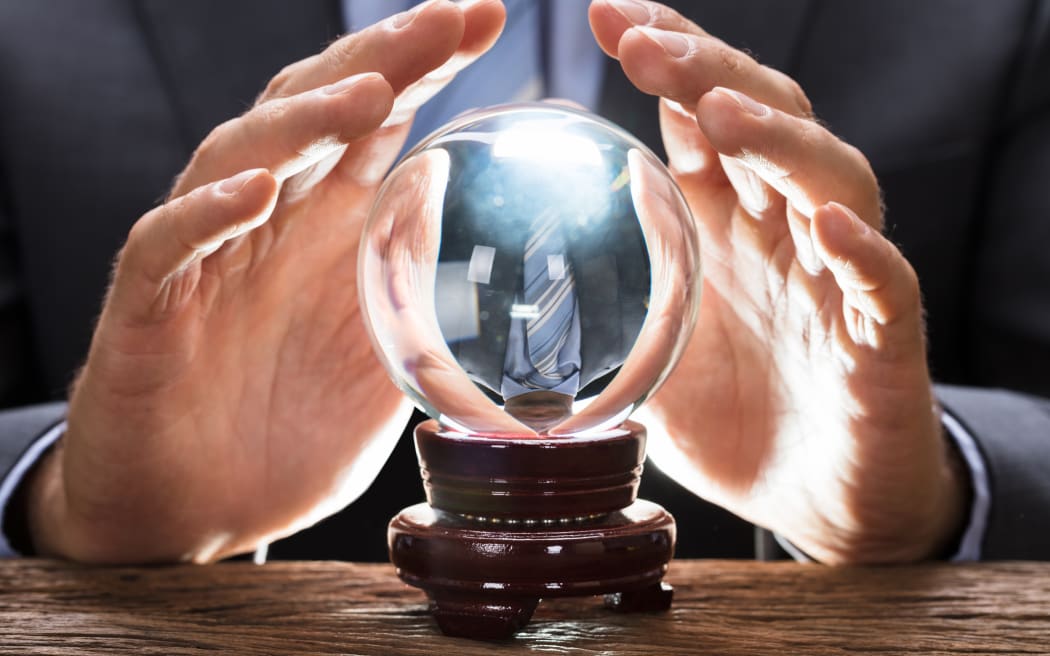 Midsection of businessman covering crystal ball at wooden table