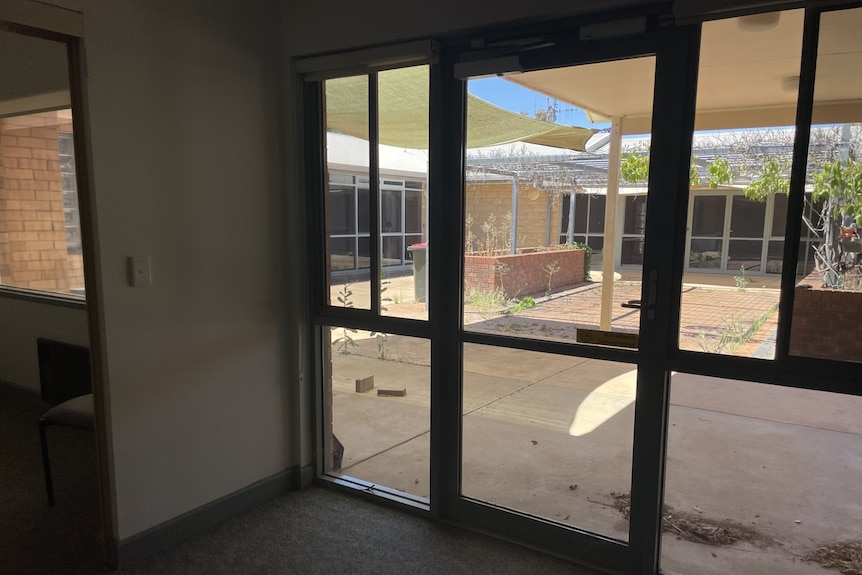 an abandoned courtyard in an aged care facility, weeds growing out of gaps in pavement.