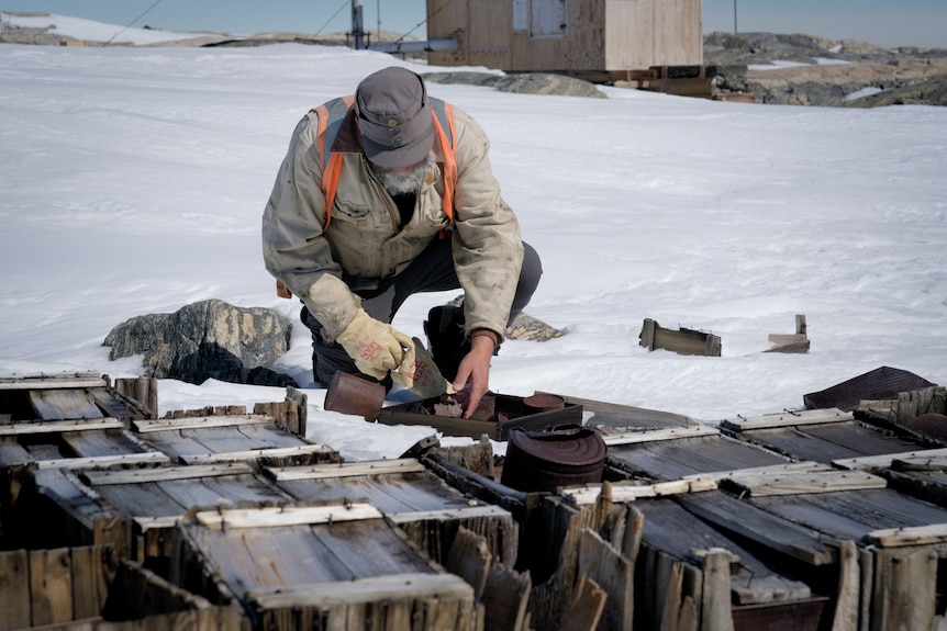 A man examines rubbish in the snow.