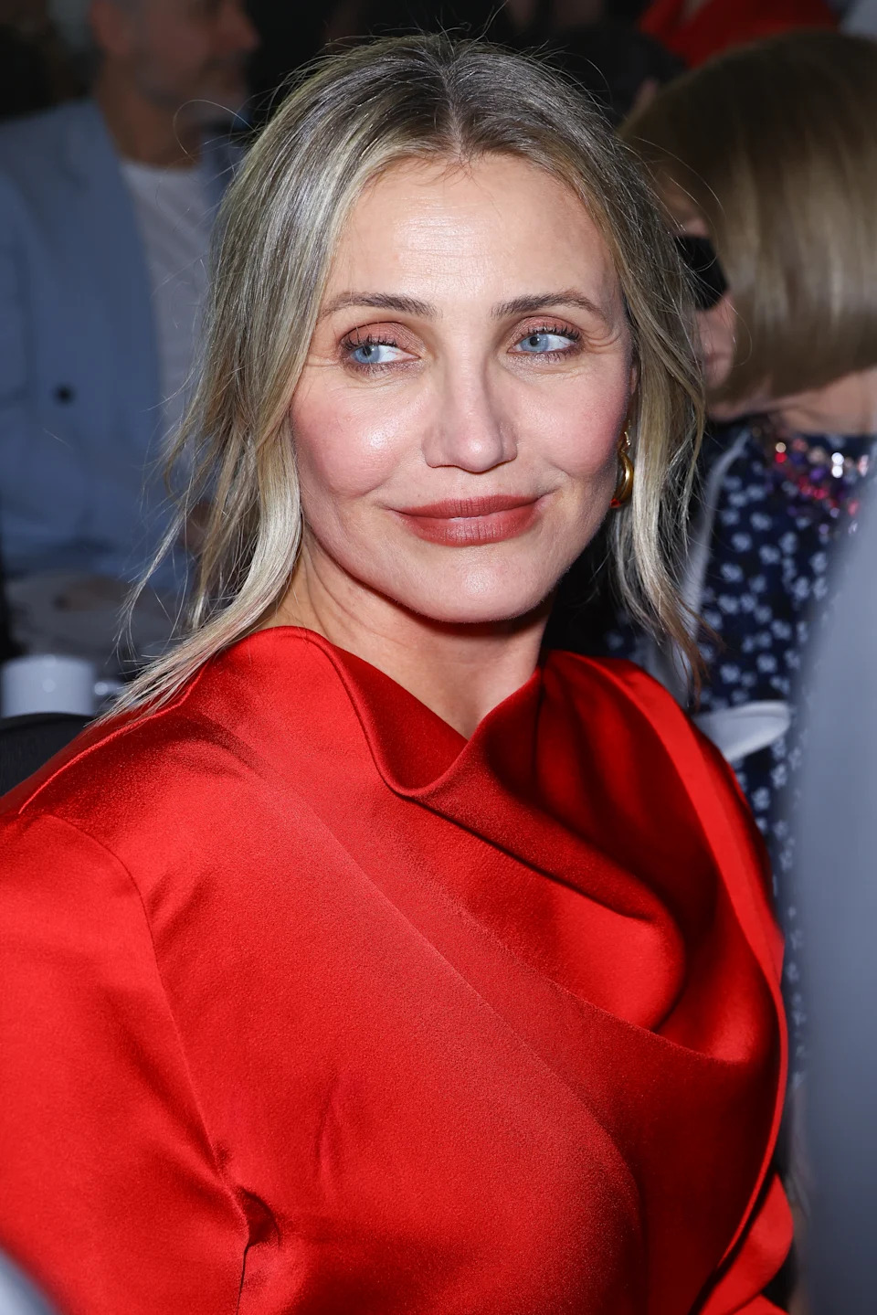 Person in an elegant draped dress at an event, smiling and looking to the side