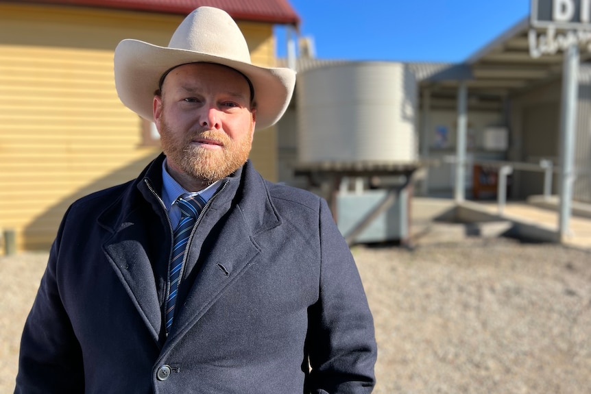 a man is wearing a large hat in a suit staring at the camera