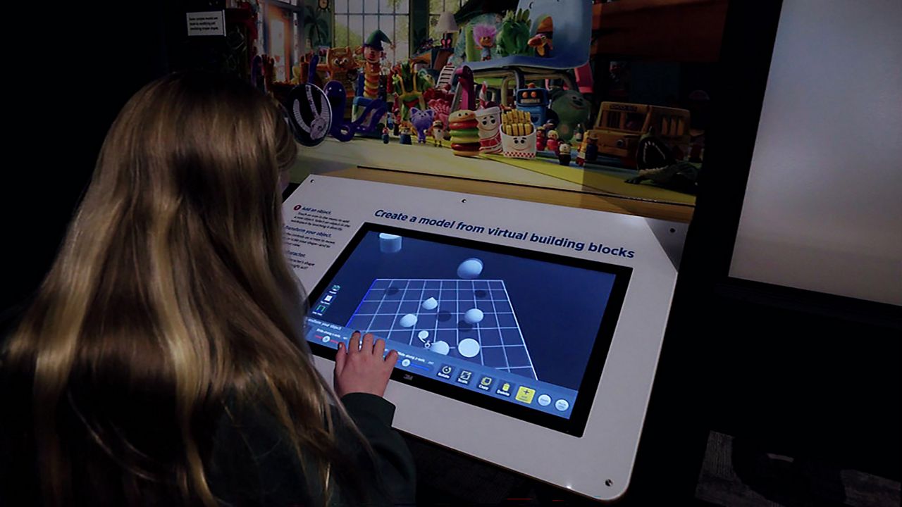Visitors interact with displays at COSI’s “Science Behind Pixar” exhibit in Columbus, Ohio, which explores the science, technology, engineering and math behind animated films. (COSI)