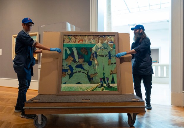 Specialists Tim Roby, left, and Chris Shepherd install Norman Rockwell's "The Dugout," an iconic painting about the Cubs, on Feb. 10, 2026, at the Art Institute of Chicago. Former Gov. Bruce Rauner and wife, Diana, gifted the painting to the museum after hanging it in their home for the past 19 years. (Brian Cassella/Chicago Tribune)