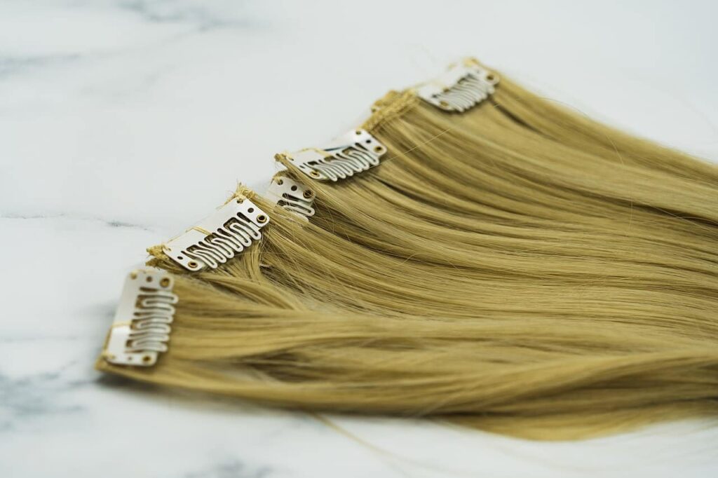 Blonde hair extensions with white clips for hair styling and volume enhancement.