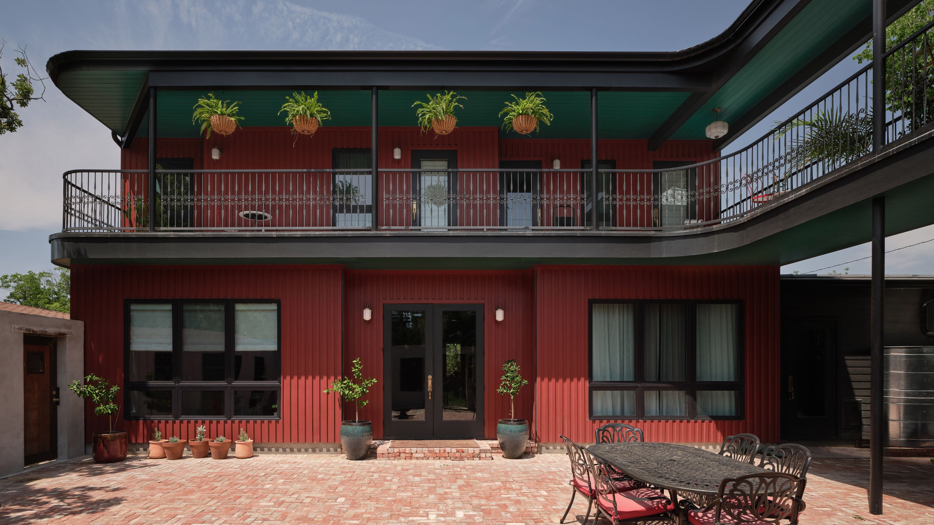 large red modern home shot from the outside with a curved balcony along it
