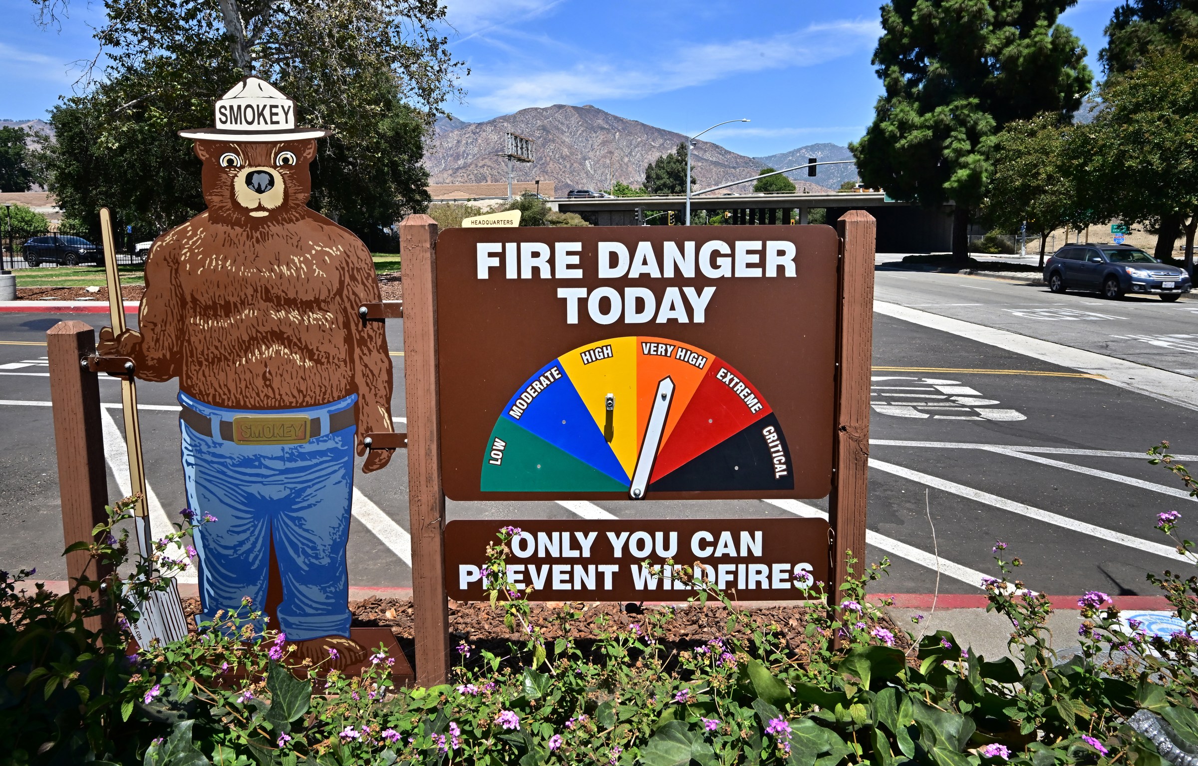 A standup of Smokey Bear next to a “Fire danger today” sign in a parking lot where it’s indicated the danger level is very high