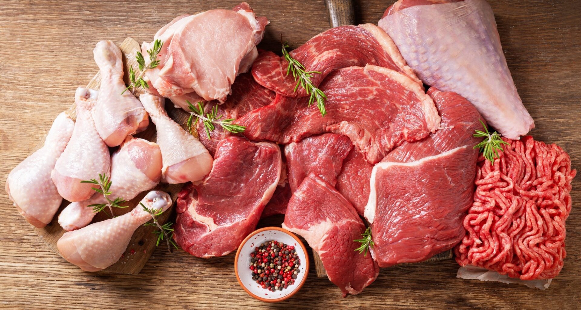 various types of fresh meat: pork, beef, turkey and chicken on a wooden table, top view