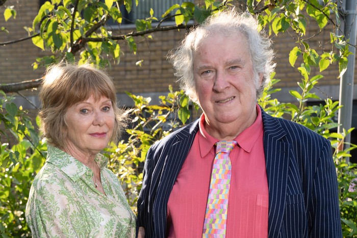 Karen Henthorn and Paul Bradley as Julie and Nigel in EastEnders. She is wearing a flowery blouse and he's wearing a navy jacket with a pink shirt and tie.