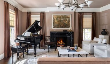 A living room with dusky pink walls, traditional decor and a large grand piano.
