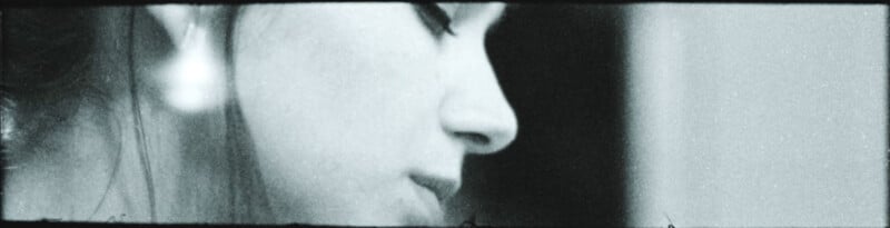 Black and white close-up of a woman's face in profile, eyes closed or looking down, with visible earring and soft, blurred details creating a contemplative mood.