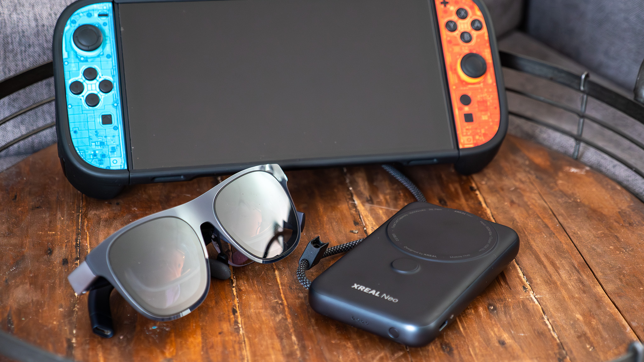 A pair of Xreal 1S glasses, an Xreal Neo, and a Nintendo Switch 2 with Dbrand skins applied to the controllers