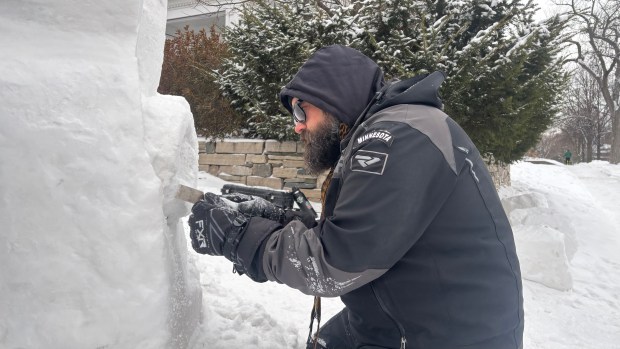 Snow sculptor Dusty Thune, who captains the multi-award-winning team House of Thune, carves what will become hands spelling "ICE OUT" in American Sign Language on a collaborative artwork near Lake of the Isles in Minneapolis on Feb. 1, 2026. A sculpture made by House of Thune, representing Team USA, was deconstructed entirely at the World Snow Sculpting Championship in downtown Stillwater over perceived anti-ICE content. (Jared Kaufman / Pioneer Press)
