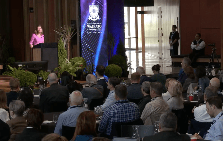 Finance Minister Nicola Willis in a pink dress at an economic forum at the University of Waikato's business forum.
