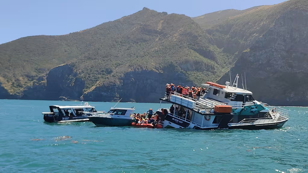 The Black Cat after the grounding. Photo shows obvious list and passengers beginning to transfer to responding boats. Photo taken by witness, supplied to TVNZ (via TIAC / Facebook).