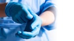 Undated photo of a health care professional donning blue medical gloves at an unspecified location.
