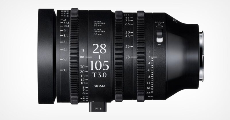 A black Sigma 28-105mm T3.0 cine zoom lens is shown from the side, displaying focus, zoom, and aperture rings with measurement markings, and a lever for adjusting settings.