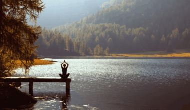 person meditating at lake