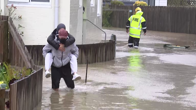 A man carries his wife to safety after floodwaters surrounded their Waiwhetu home.