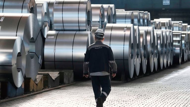 A steel worker walks beside steel coils during a visit of EU Commissioner for Prosperity and Industrial Strategy Stephane Sejourne at the Thyssenkrupp steelworks in Duisburg, Germany, after the EU Steel Action plan was presented, Thursday, March 20, 2025.