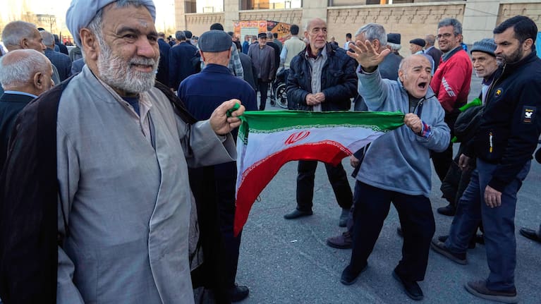 A worshipper chants slogan as he holds an Iranian flag with a cleric after the conclusion of the Friday prayers ceremony at the Imam Khomeini Grand Mosque in Tehran, Iran